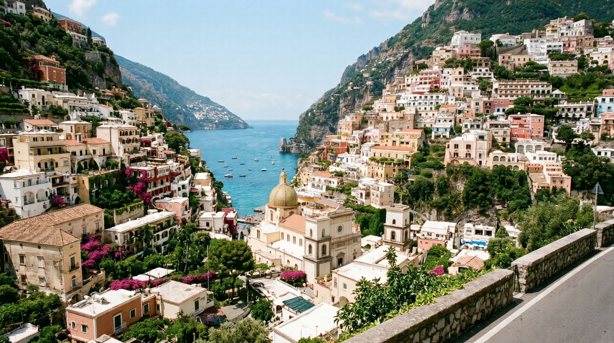 Aerial view of Positano on the Amalfi Coast with cascading pastel terracotta and whitewashed buildings the majolica church dome and deep aquamarine sea below under a cobalt blue sky