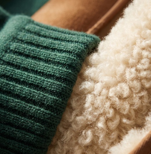 Macro close-up of pine green cashmere knit texture against cognac shearling boot lining