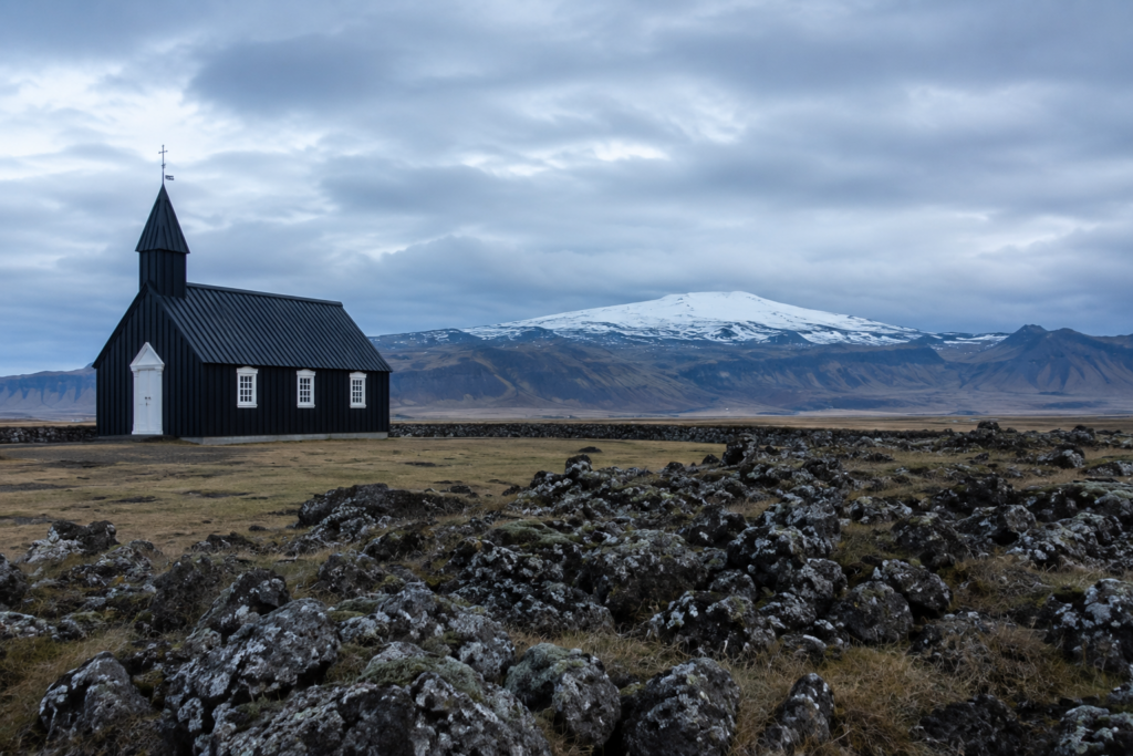Black wooden church at Búðir on Iceland's Snæfellsnes Peninsula with a glacier volcano behind it