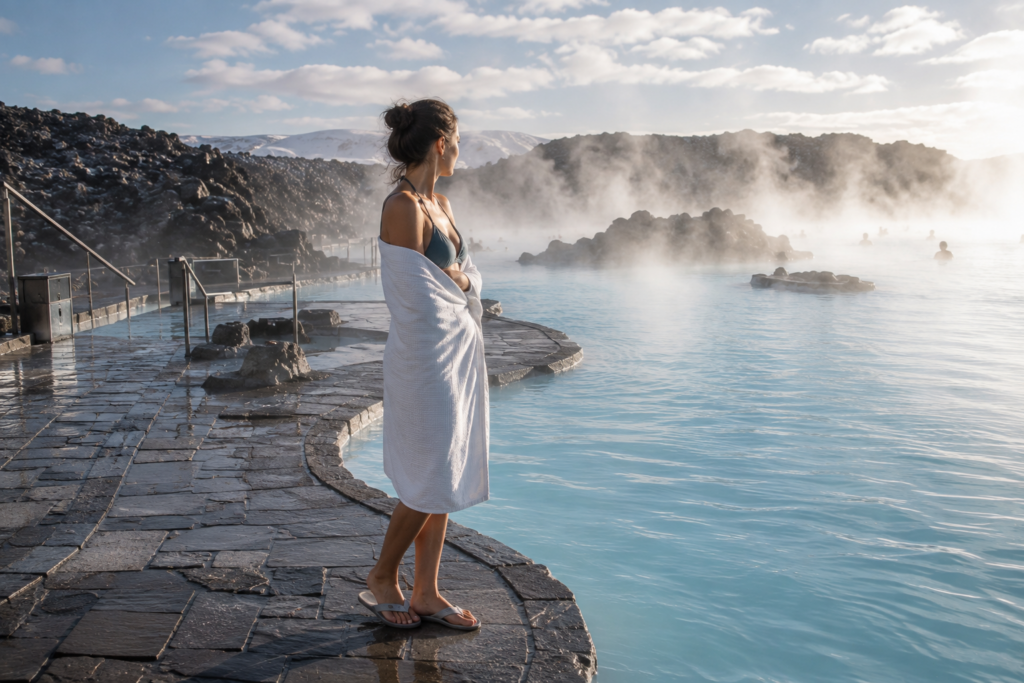 Woman at an Iceland geothermal pool wrapped in a towel with steam rising off the water