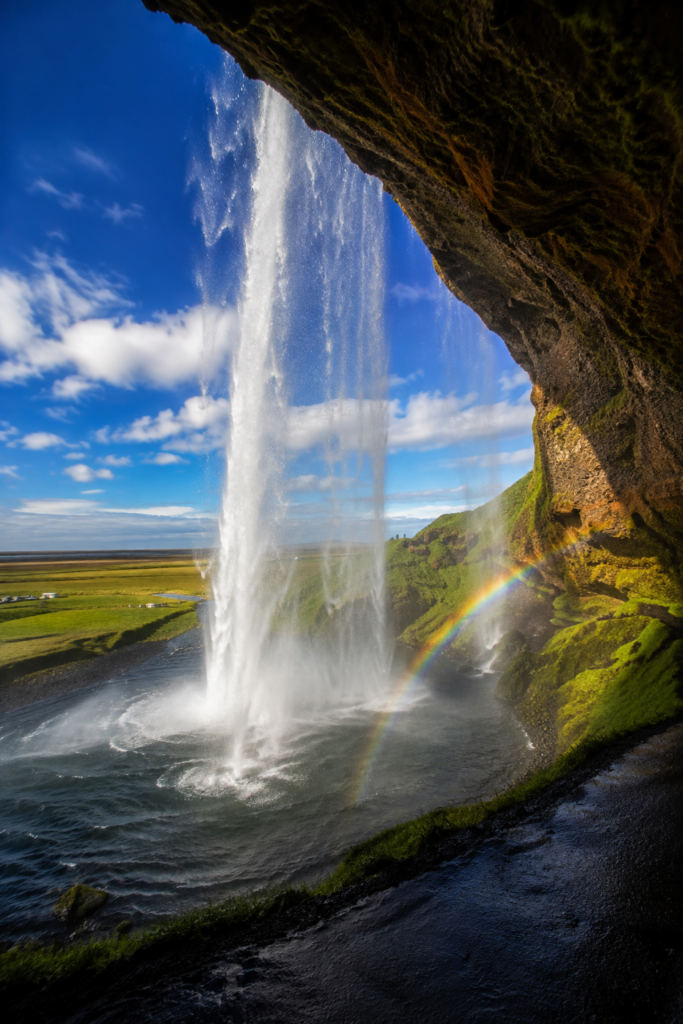 Looking out through Seljalandsfoss waterfall from the path behind the falls